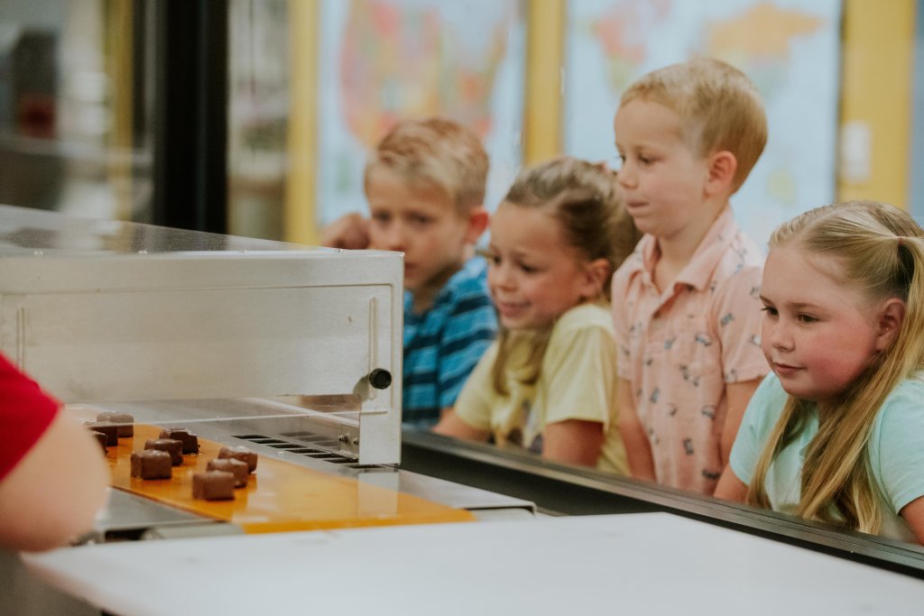 Children watching chocolate candies move along a conveyor belt during a factory tour at Susie’s South Forty Confections in Midland, Texas.